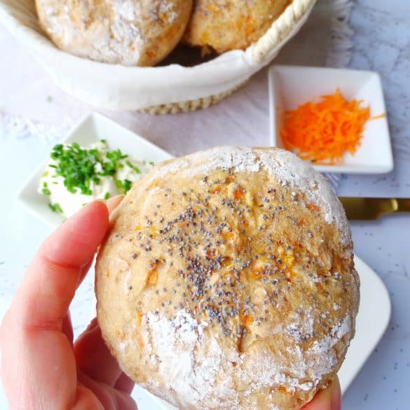 Karottenbrötchen mit Mohn in der Hand gehalten