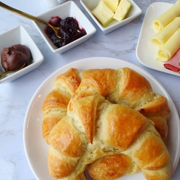 Croissants auf weißem Teller mit Frühstückszutaten